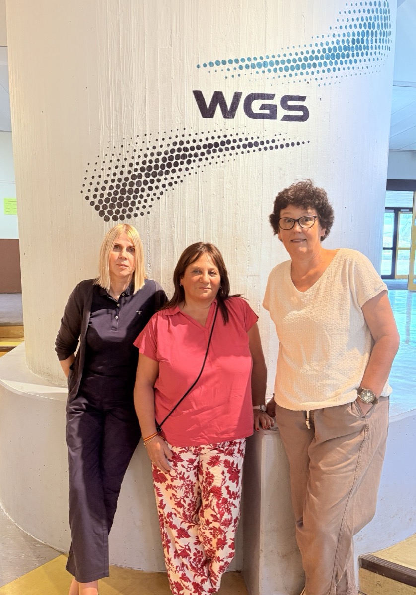 Das Team der Hausaufgabenbetreuung vor der Säule mit dem WGS-Logo in der Pausenhalle