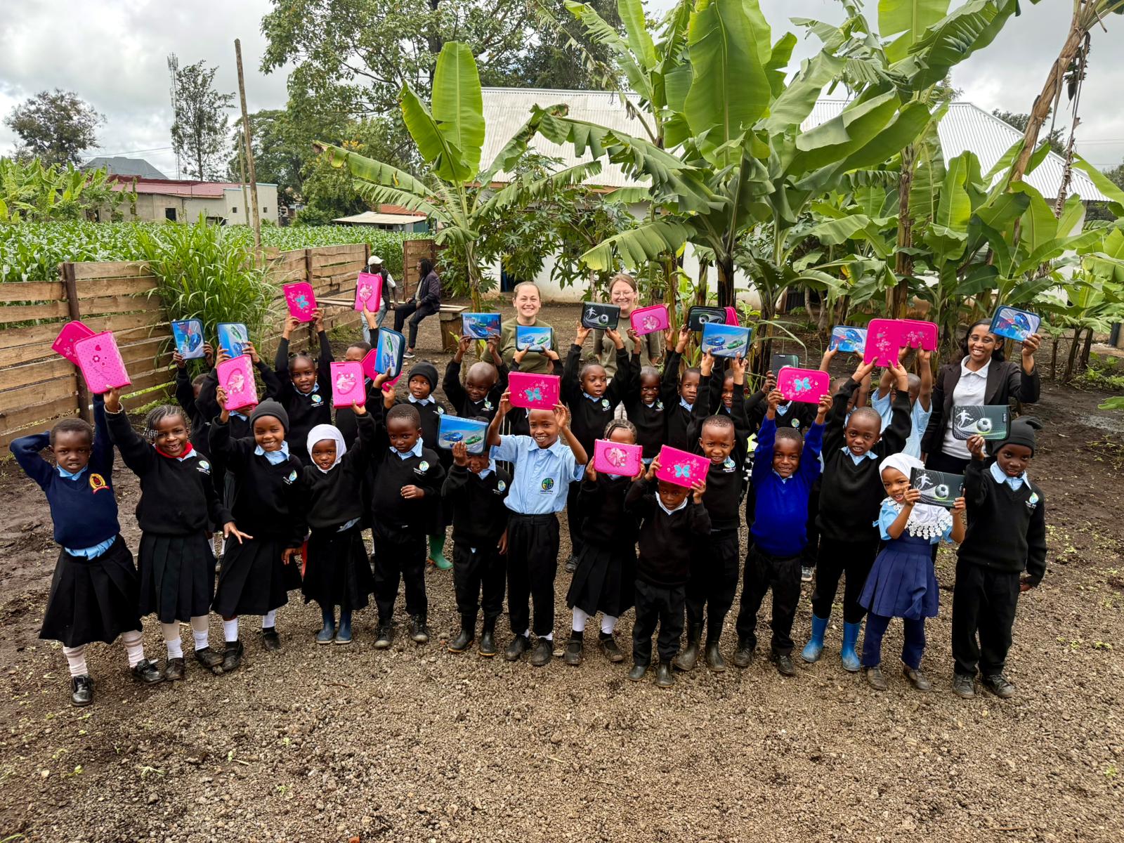 Die Kinder der MILELO Primary School halten ihre neuen Schulmäppchen lachend in die Höhe
